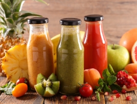 フルーツに囲まれたオレンジとグリーンとトマトのジュース